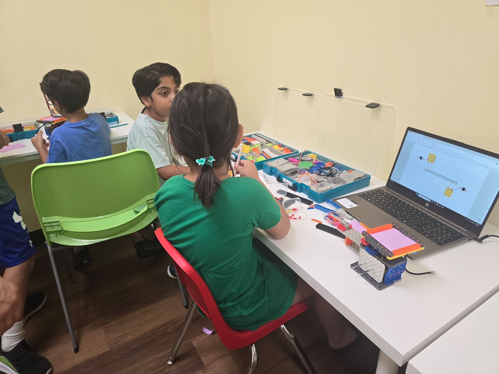 Campers building robots with a build guide open on a laptop