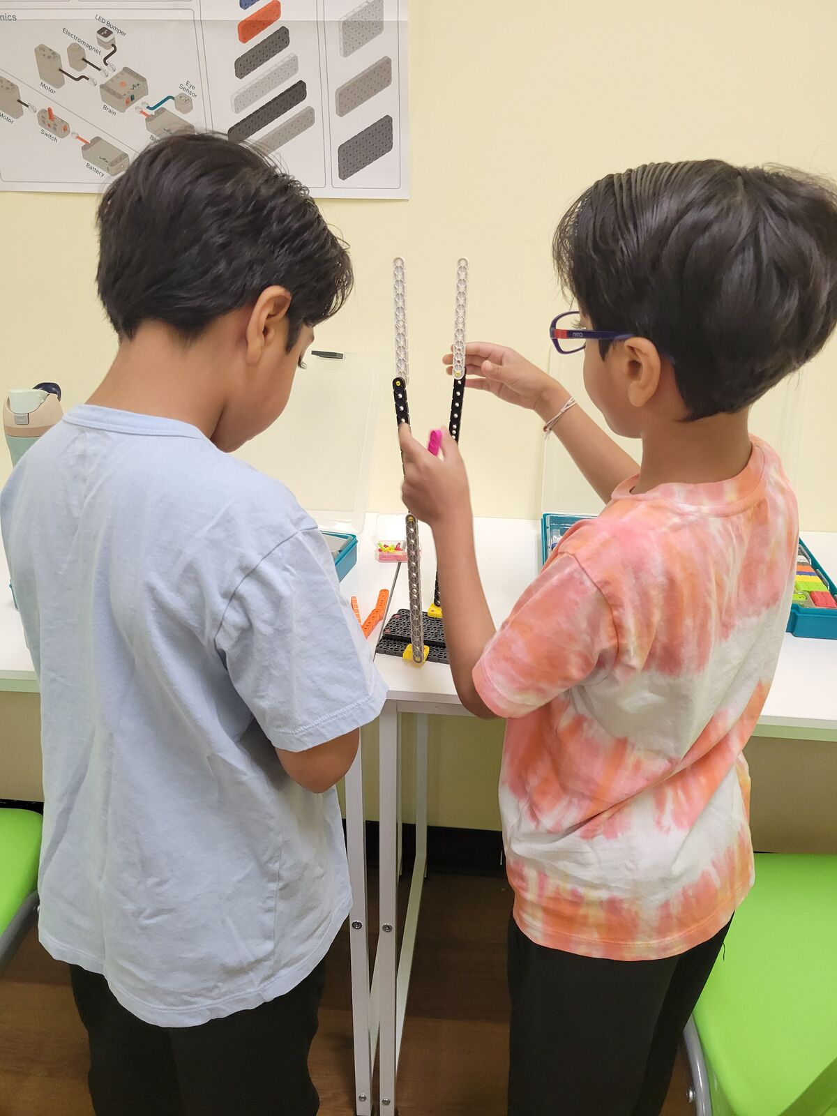 Two campers building a structure from robotics beams