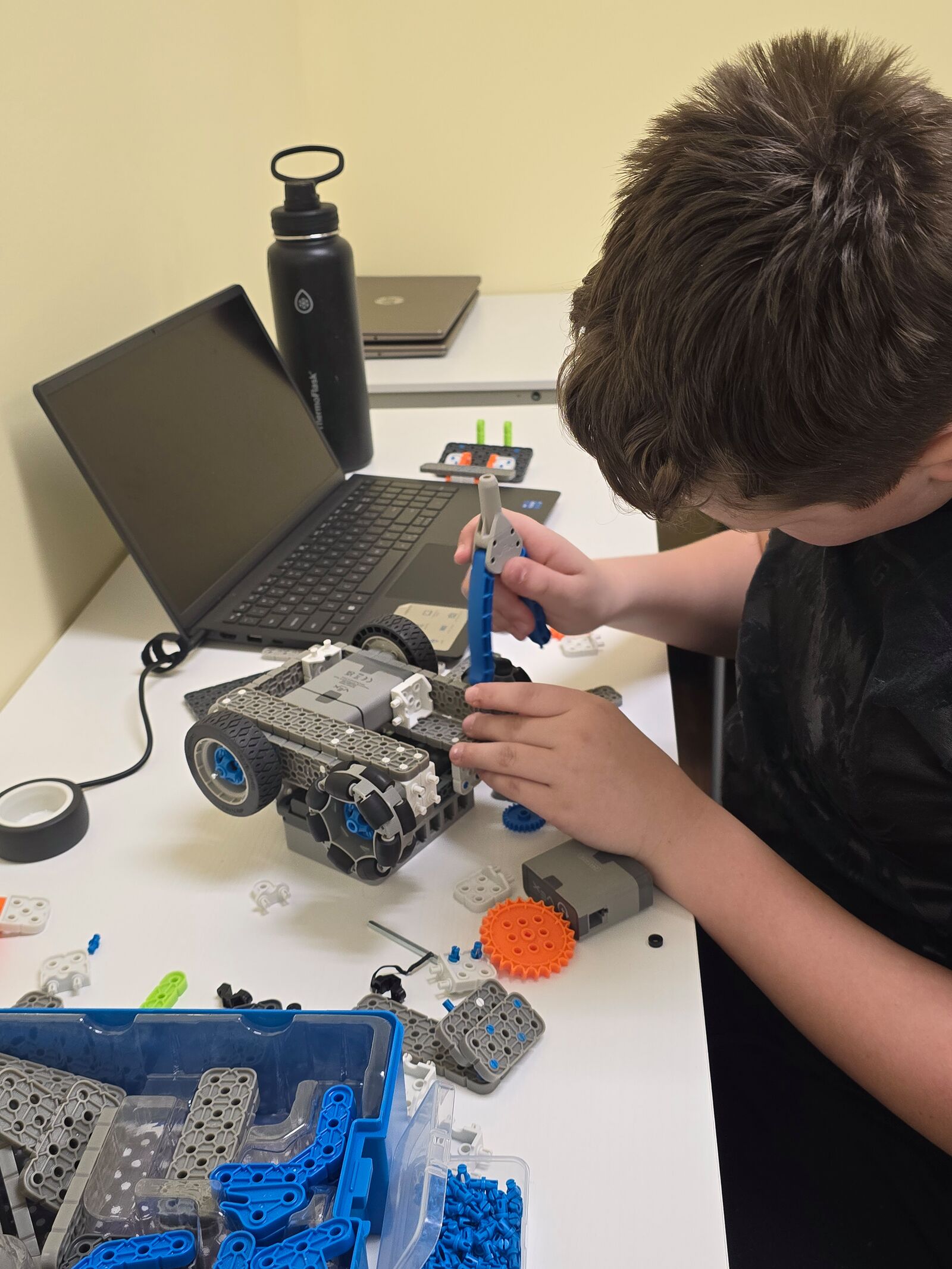 A student attaching parts to a robot at a workbench