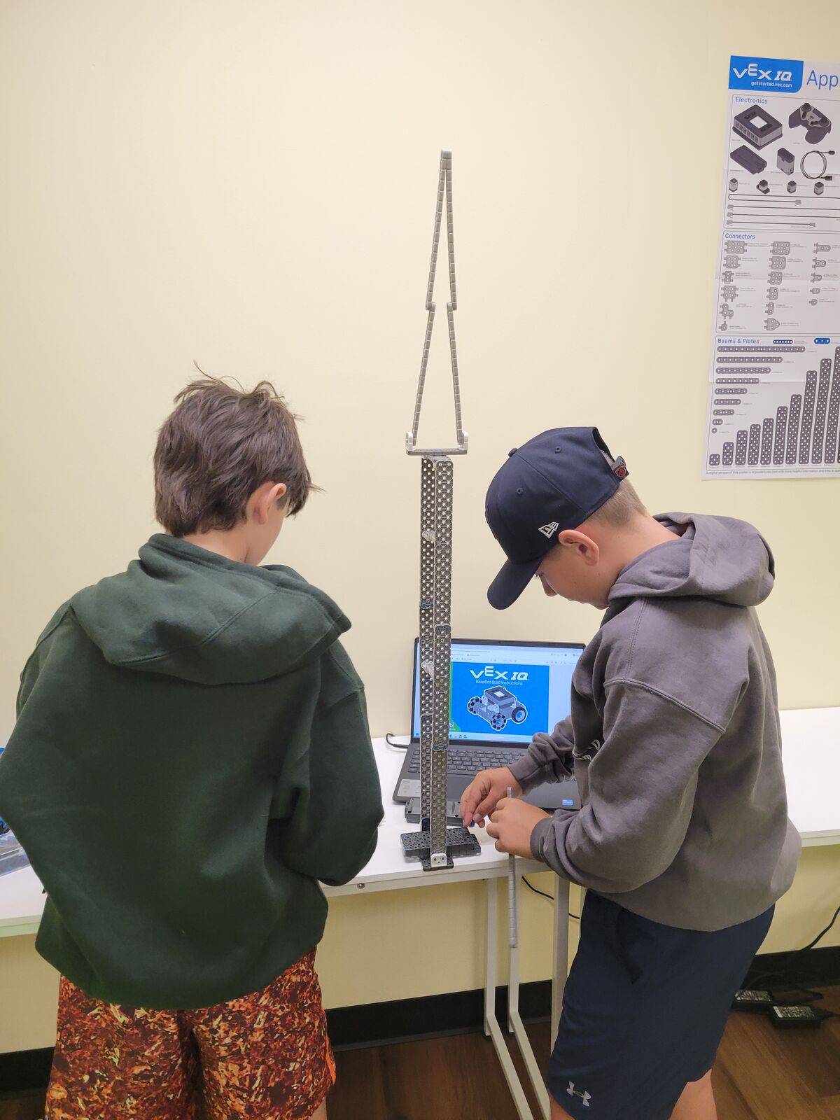 Two students building a tall structure from VEX IQ parts